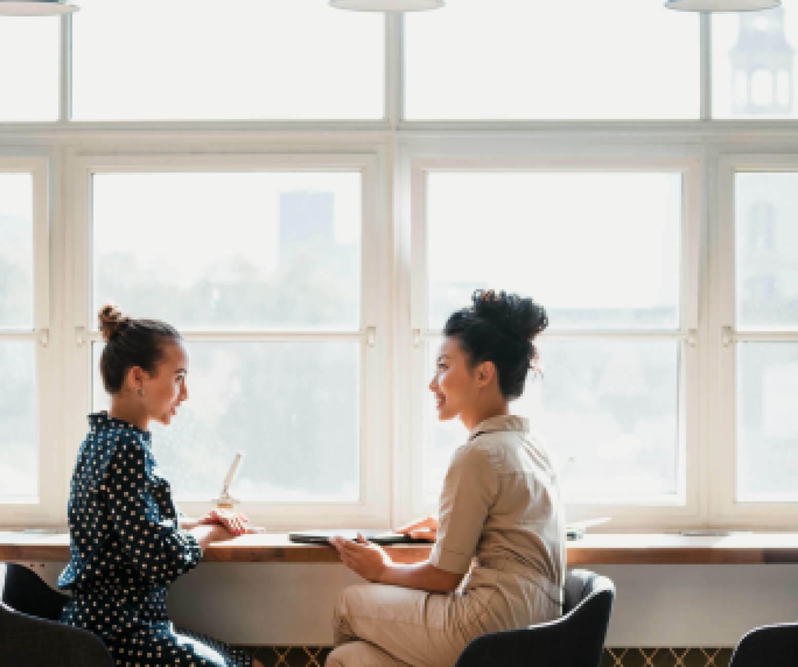 Two women chatting by a window