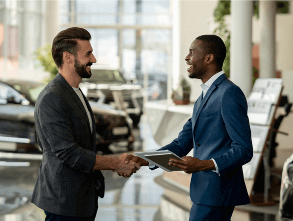 An automotive sales agent shaking hands with a customer
