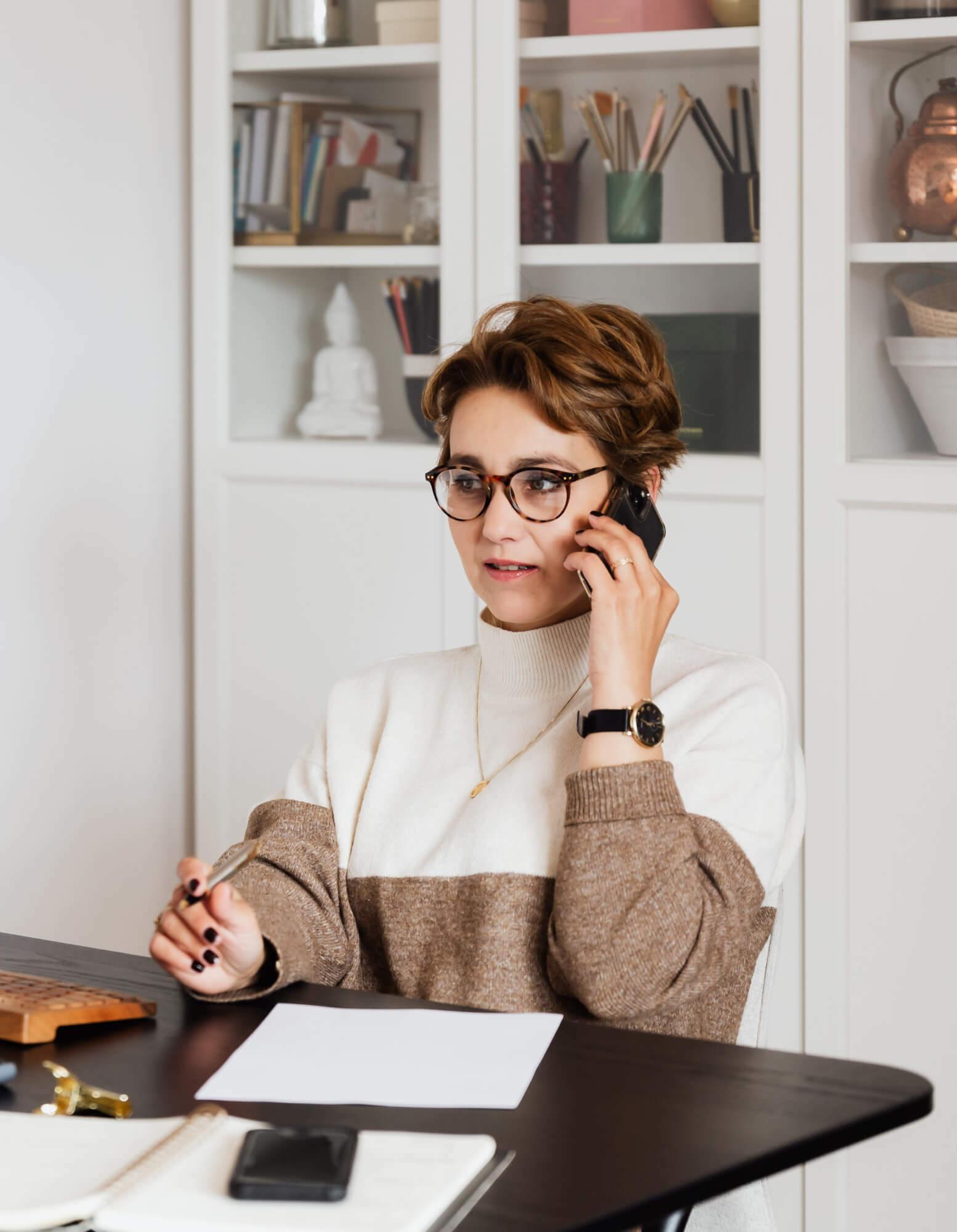 A woman at her desk in her home office, while on a phone call