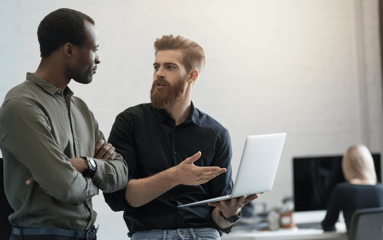 Two people standing next to each other having a discussion in an office