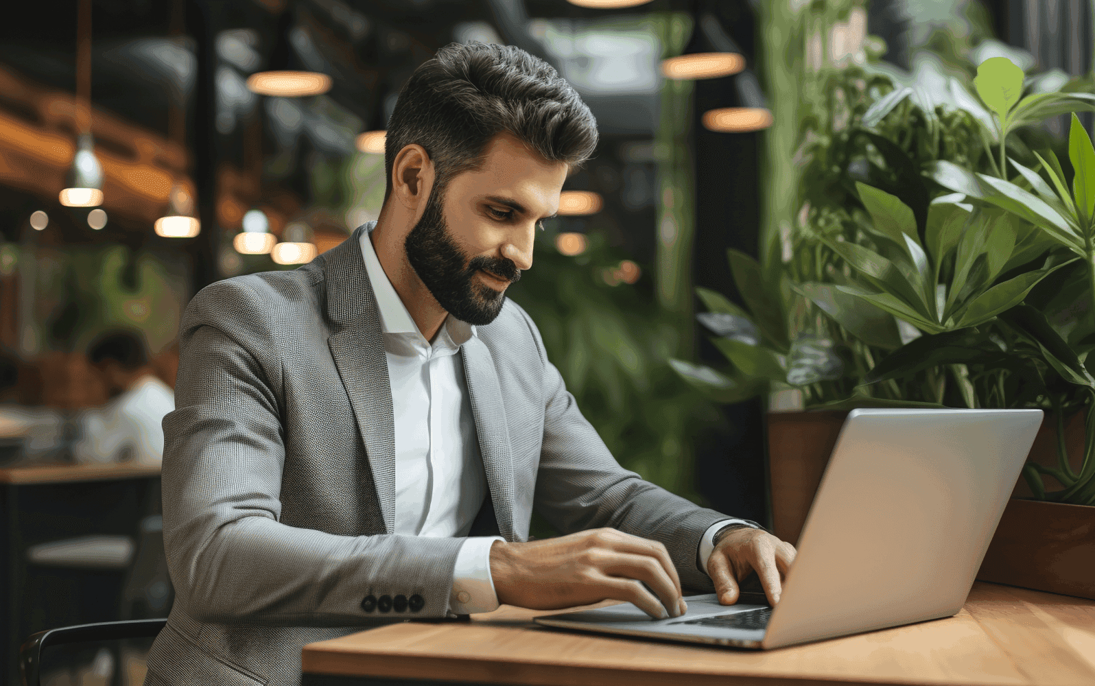 Man wearing a suit sitting at a desk with a laptop in front of them